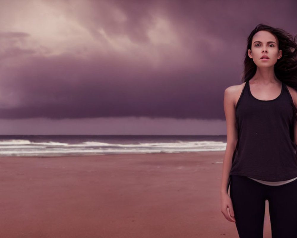 Woman with flowing hair on beach under stormy clouds.