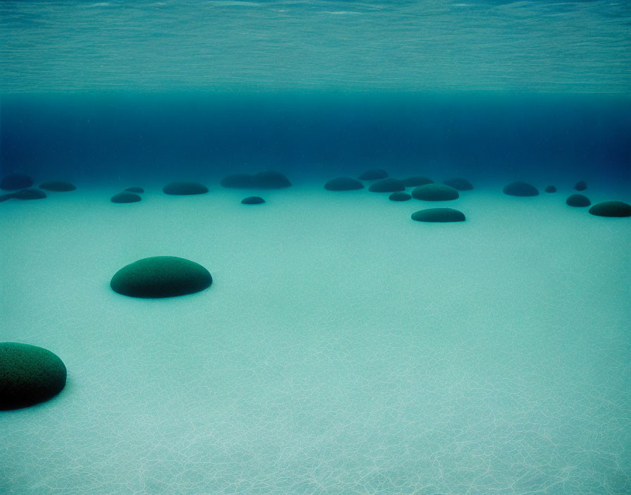 Tranquil underwater scene with smooth dark stones on sandy bottom