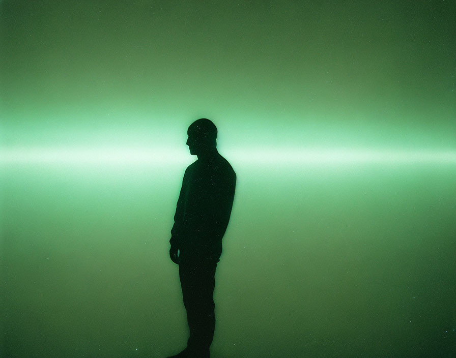 Person silhouette against glowing green backdrop with horizontal light stripe