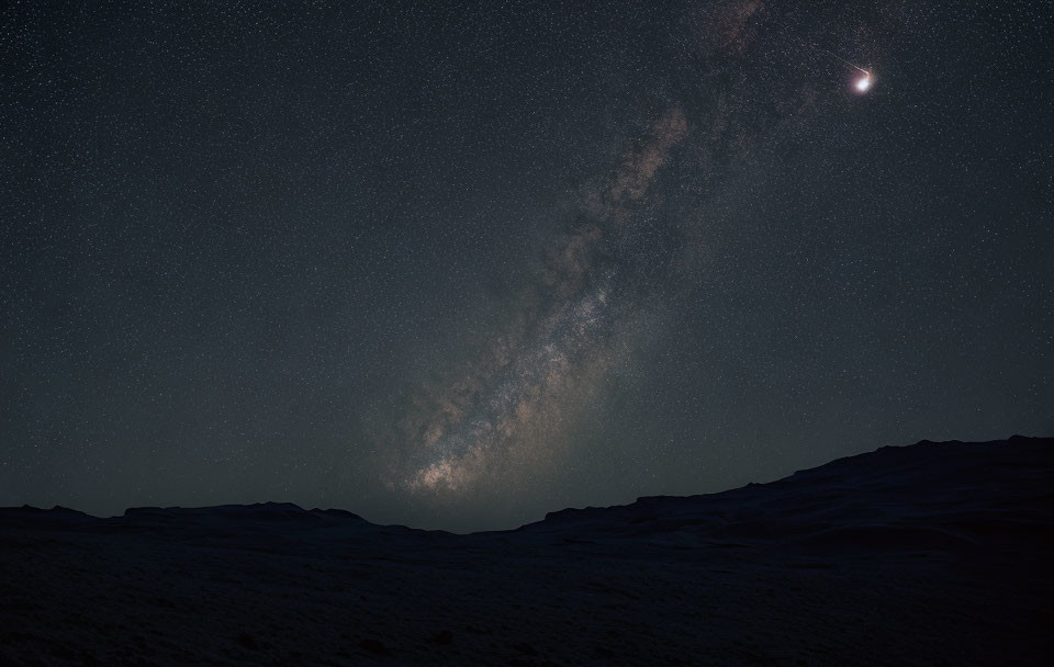 Starry night sky with Milky Way, crescent moon, and landscape.