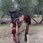 Woman in leather jacket with brown horse in magical setting