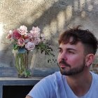 Profile of a man with a well-groomed beard next to white flowers and pink blossoms.