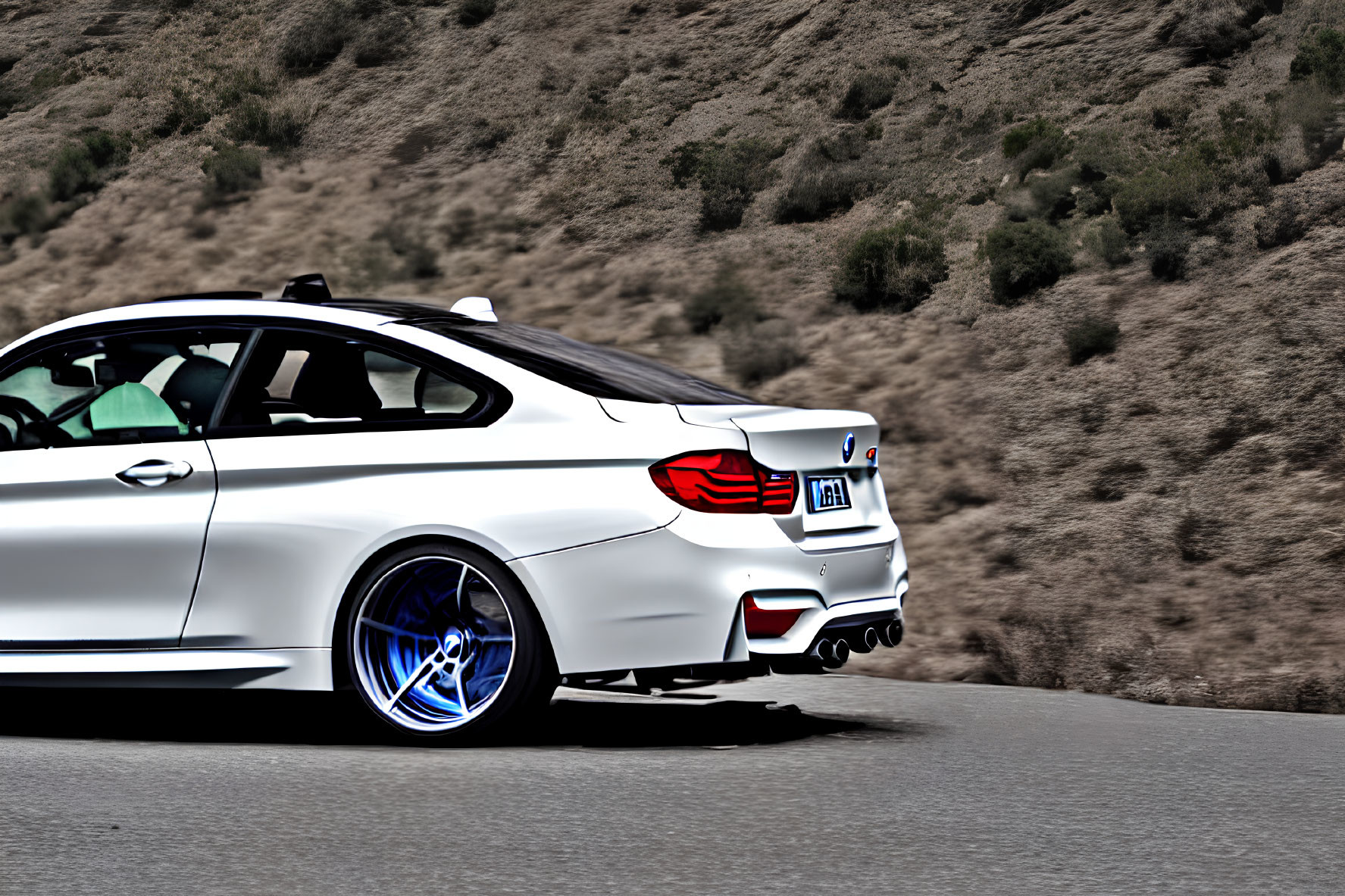 White Sports Car with Blue-Tinted Wheels on Mountain Road