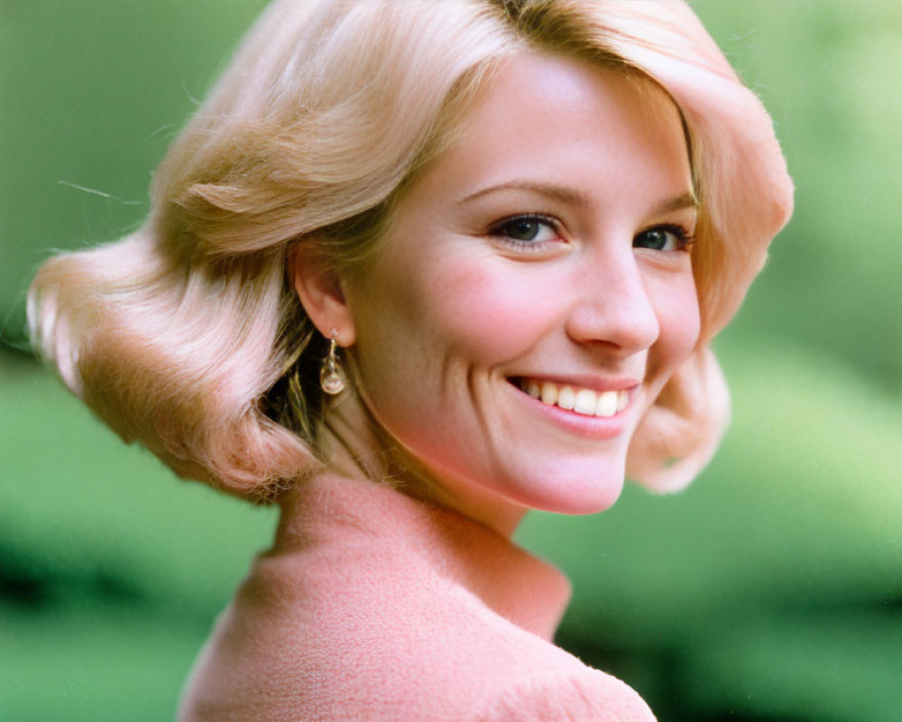 Blonde Woman Smiling in Pink Outfit on Green Background