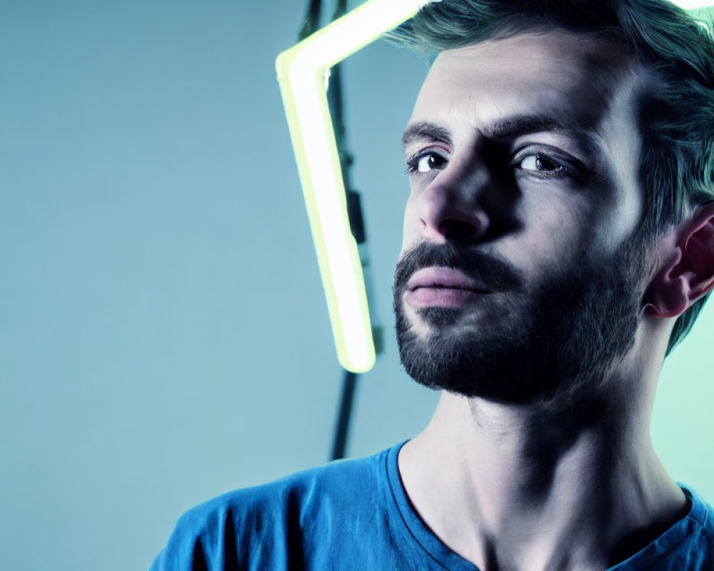 Bearded man in cool-toned light with neon background