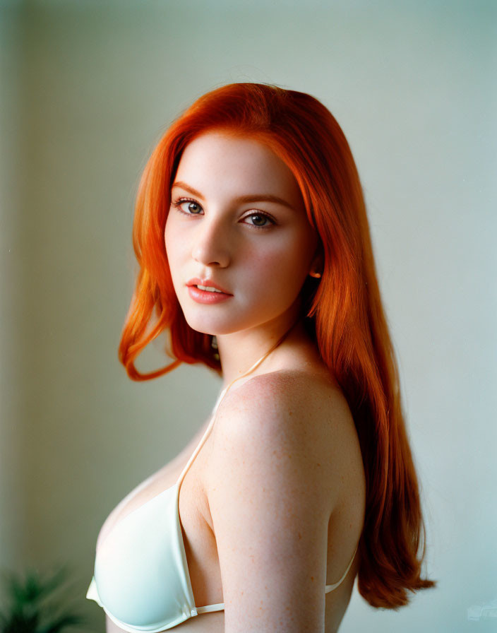 Red-haired woman in white top with freckles staring at camera