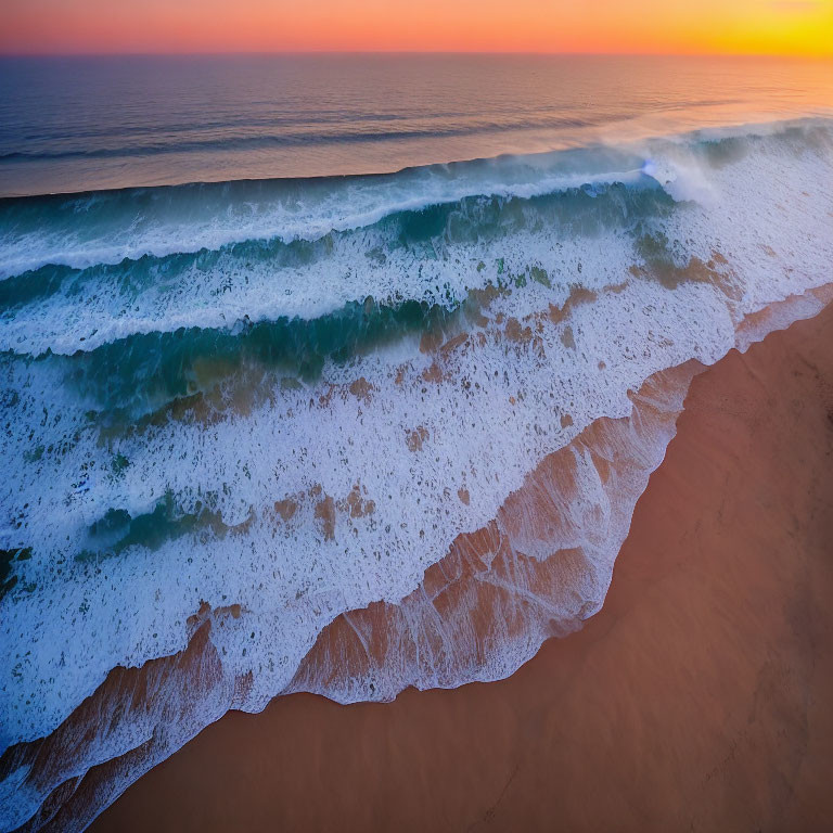 Aerial View of Sunset Shoreline with Rolling Waves and Sandy Beach