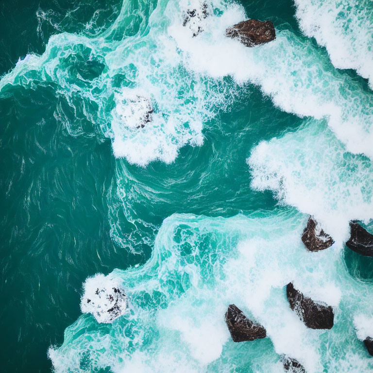 Aerial View: Turquoise Ocean Waves Crashing on Dark Rocks