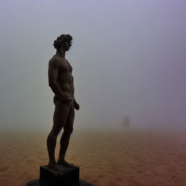 Muscular male figure statue on misty day with person walking away