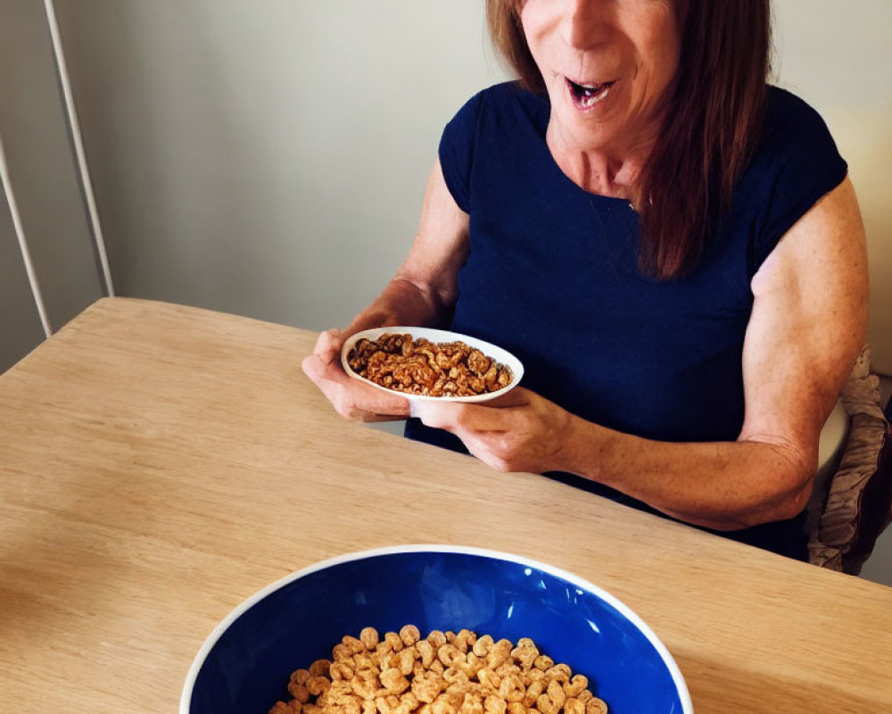 Brown-haired woman in dark blue top smiling with cereal bowl