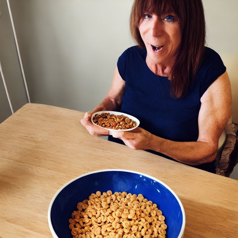 Brown-haired woman in dark blue top smiling with cereal bowl