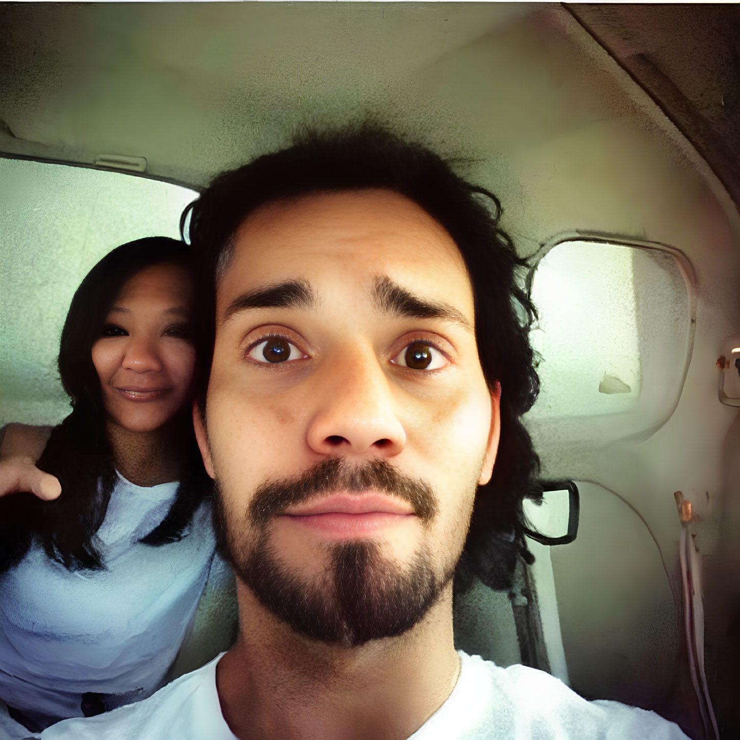 Bearded man and smiling woman in vehicle interior