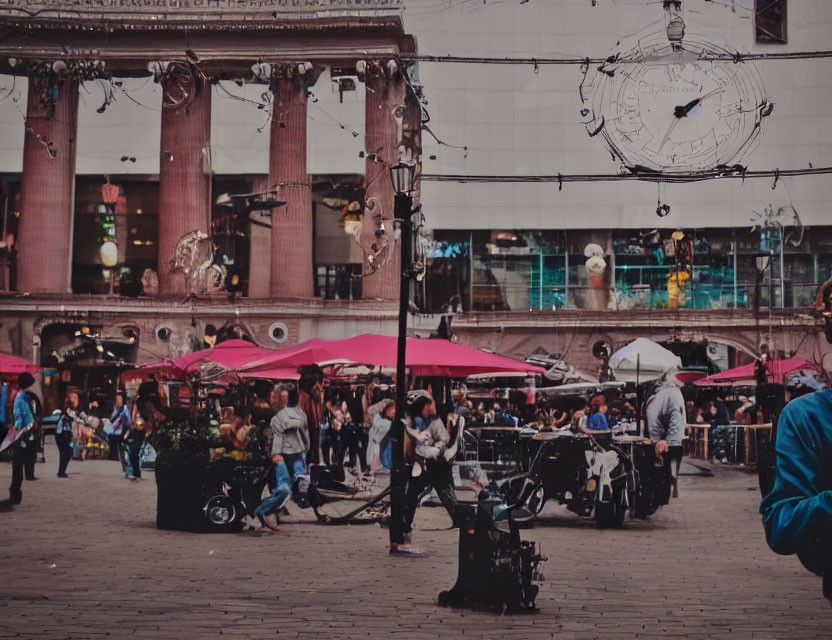 Busy city square with people, umbrellas, street lamps, and ornate clock