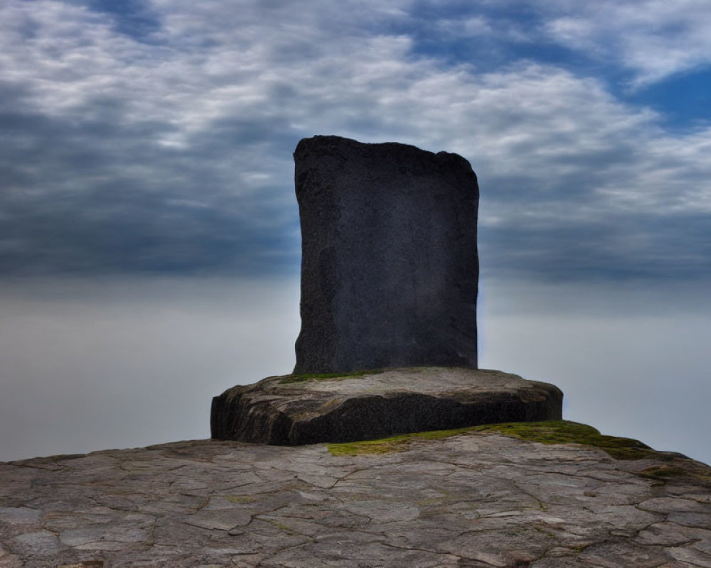 Weathered monolith on cobblestone under dramatic sky