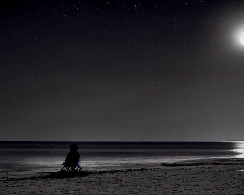 Solitary figure on beach at night under starry sky and bright moon.