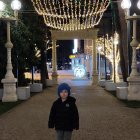 Boy with backpack on cobblestone path gazes at magical illuminated street