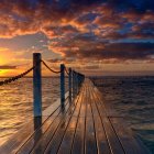 Woman in flowing dress on reflective surface with colorful abstract shapes at sunset