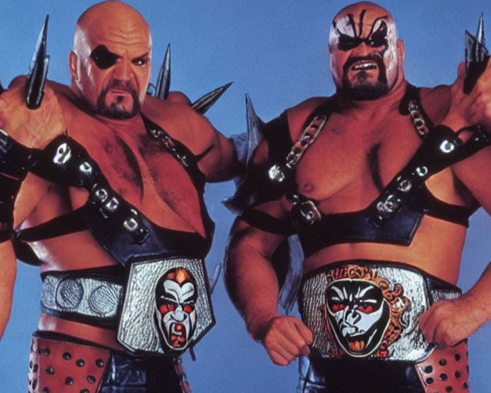 Muscular wrestlers with face paint, spiked shoulder pads, and championship belts