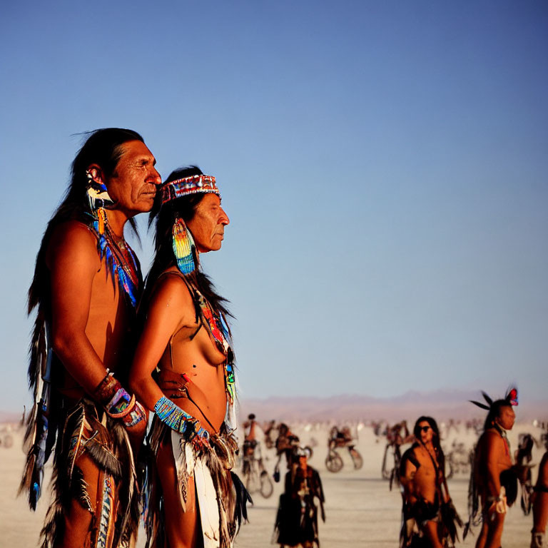 Native American attire individuals at desert event with bikes in background