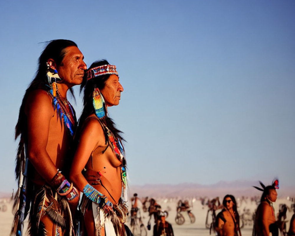 Native American attire individuals at desert event with bikes in background