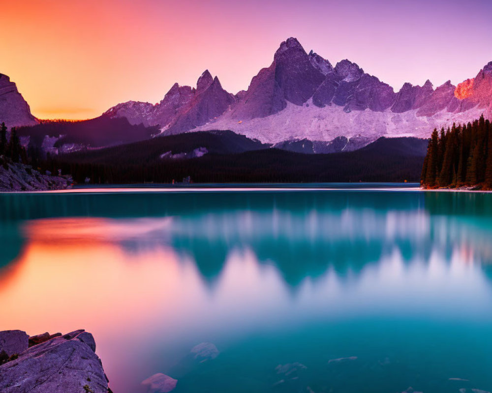 Scenic sunset over mountain range with pink and orange skies reflected in blue lake