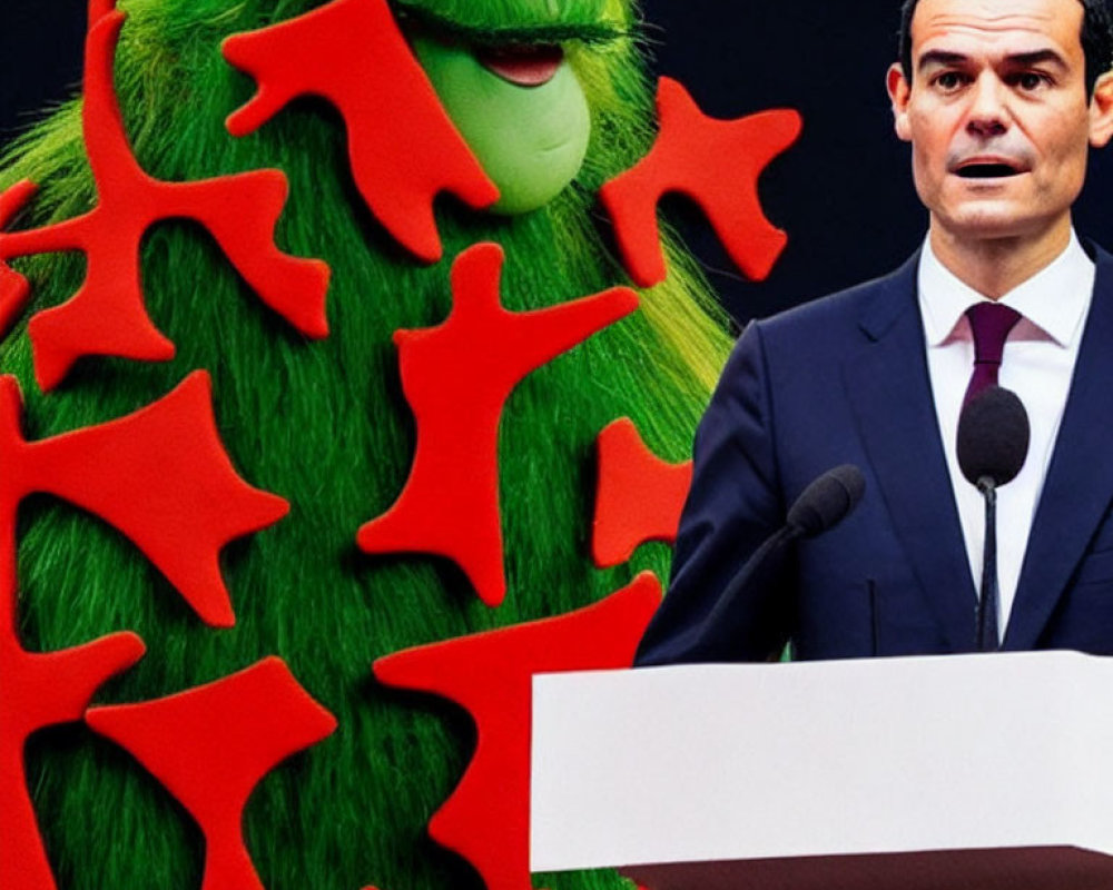 Man in suit at podium with green furry creature with red star patterns