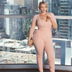 Stylish woman in peach bodysuit with cut-outs poses confidently in city backdrop