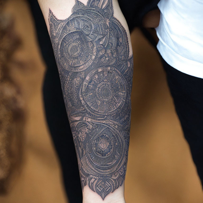 Detailed black-ink forearm tattoo with intricate geometric mandala patterns