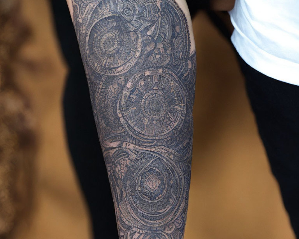 Detailed black-ink forearm tattoo with intricate geometric mandala patterns