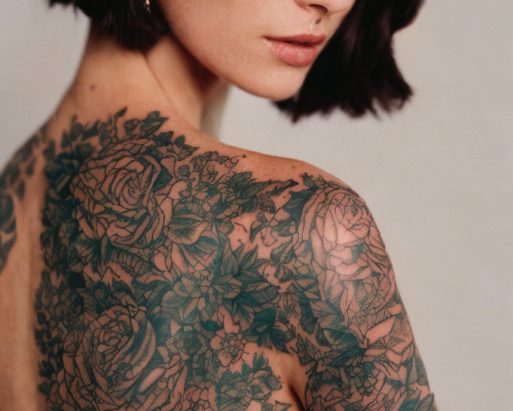 Woman with Short Dark Hair and Nose Ring Revealing Intricate Floral Back Tattoo