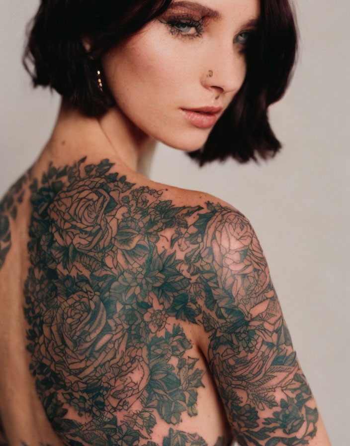 Woman with Short Dark Hair and Nose Ring Revealing Intricate Floral Back Tattoo