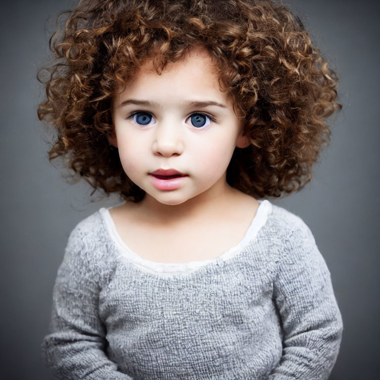 Curly-Haired Child with Blue Eyes in Grey Top