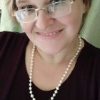 Smiling young woman with braided hair and pearl necklace in warm sunlight