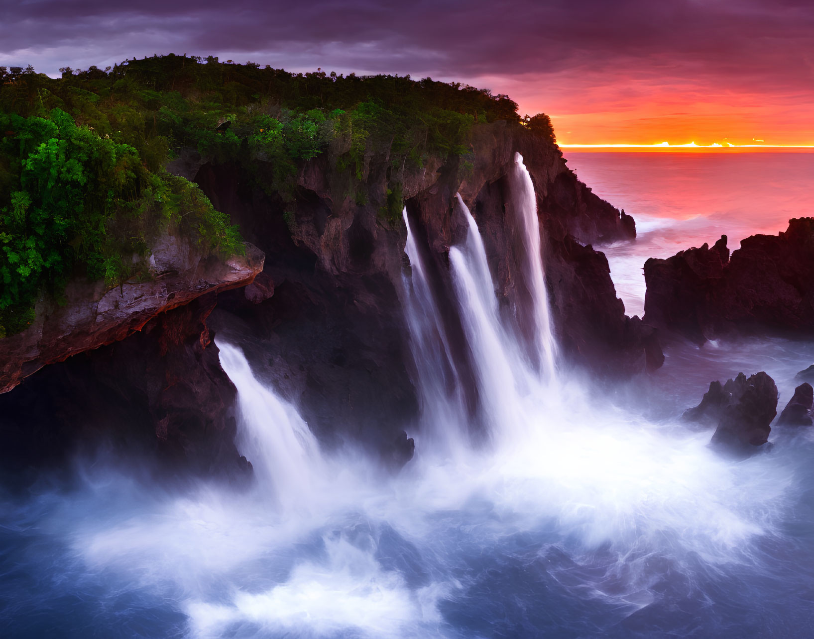 Majestic waterfall cascading into ocean at vibrant sunset