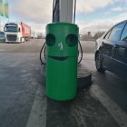 Colorful illustration of small blue creature at futuristic gas station