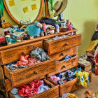 Messy dresser with overflowing drawers in room with green walls