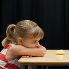 Young girl with ponytail gazes at cupcake in dim lighting