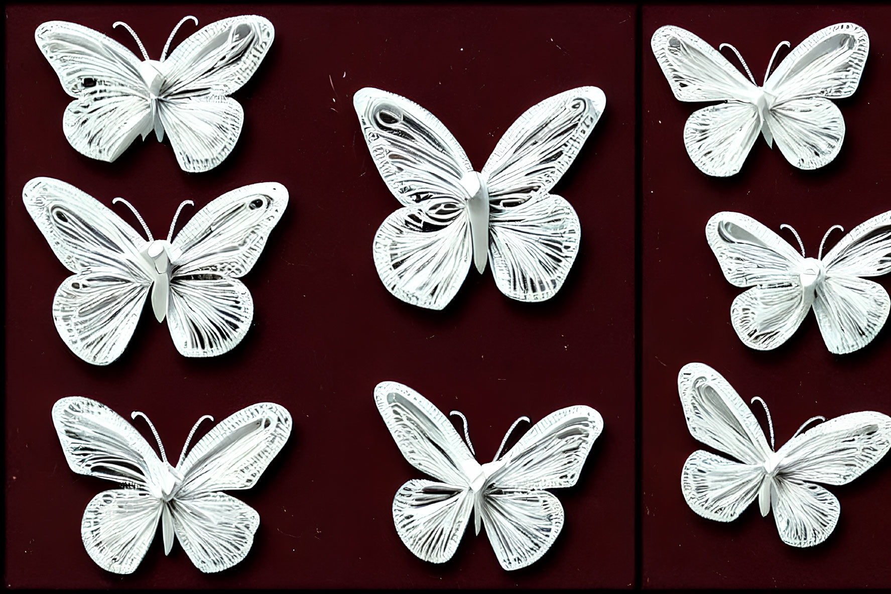 Symmetrical Display of Six White Butterfly Figures on Dark Red Background