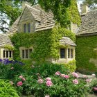 Quaint Thatched-Roof Cottage Surrounded by Lush Greenery and Colorful Blossoms