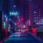 City bridge at night with vehicles, streetlights, skyline, and colorful lights.