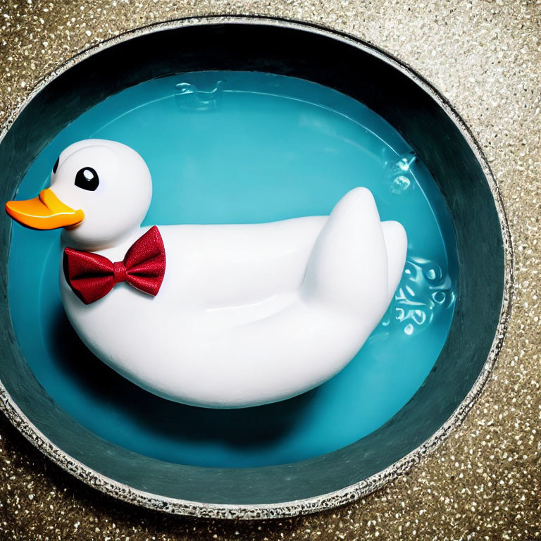 Stylish rubber duck with red bow tie in blue water on golden background