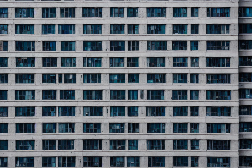 High-rise building facade with dense grid of windows in urban setting.