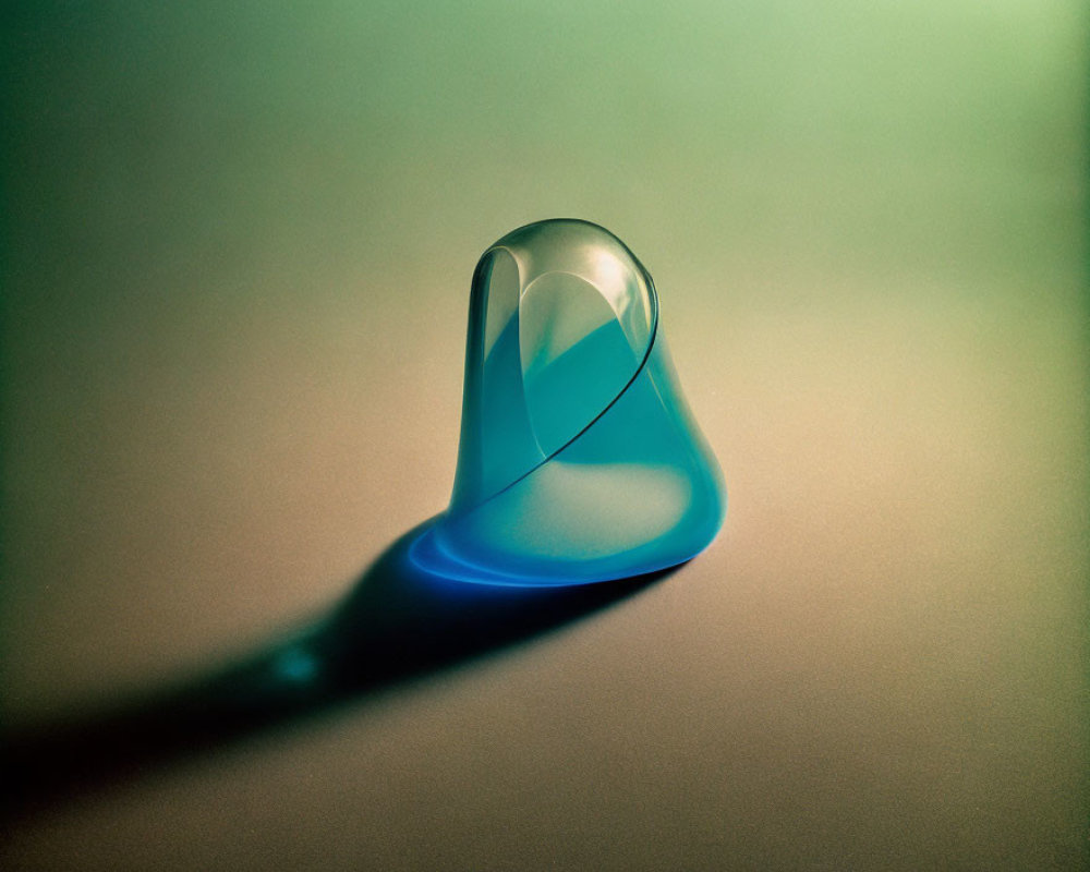 Transparent Glass Droplet Casting Blue Shadow on Gradient Green-and-Tan Surface