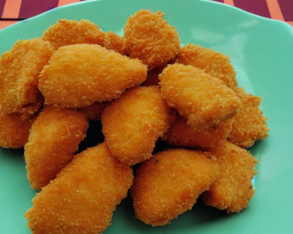 Golden-brown Breaded Chicken Nuggets on Turquoise Plate with Striped Background