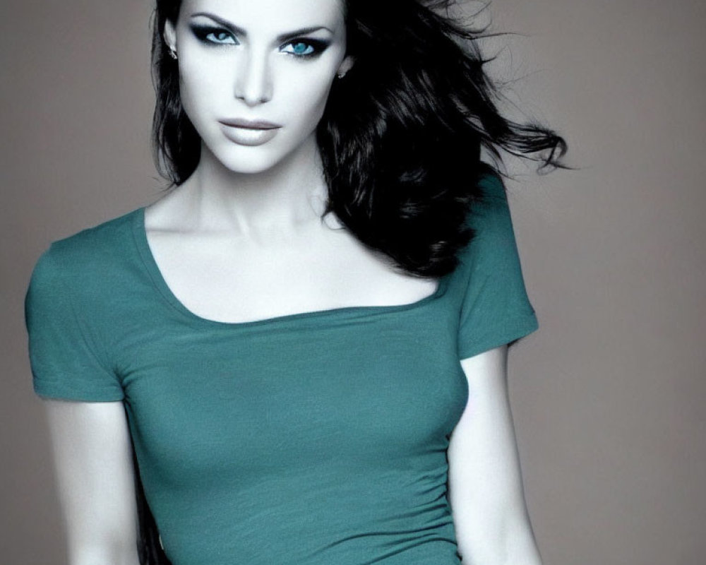 Striking blue-eyed woman in green top against gray backdrop