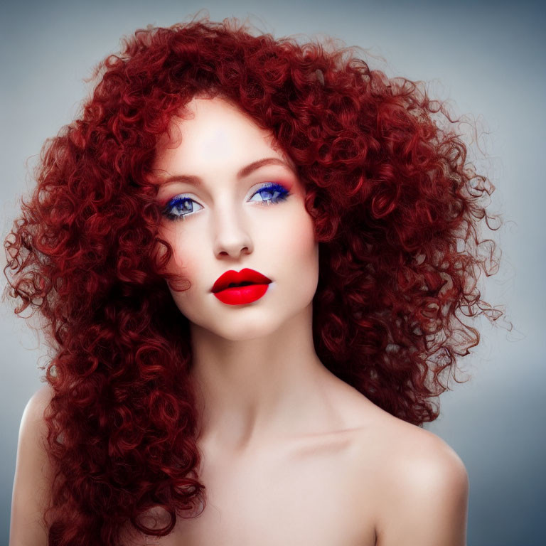 Voluminous red curly hair, blue eyeshadow, and red lipstick on woman portrait