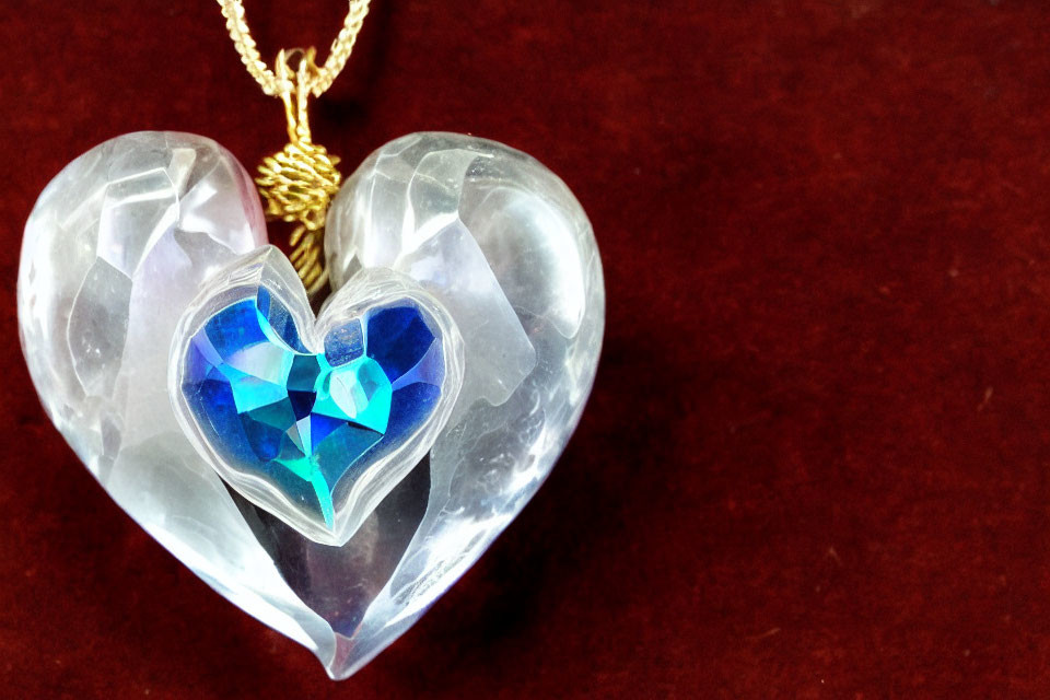 Heart-shaped crystal pendant with blue heart, gold chain, red background