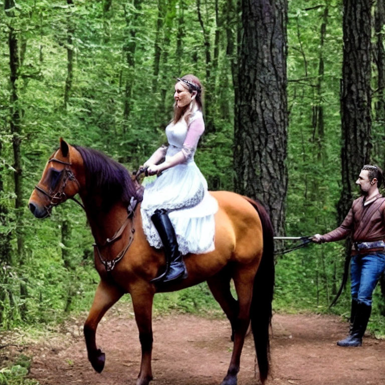 Bride in white dress on horse led by man in leather jacket through forest