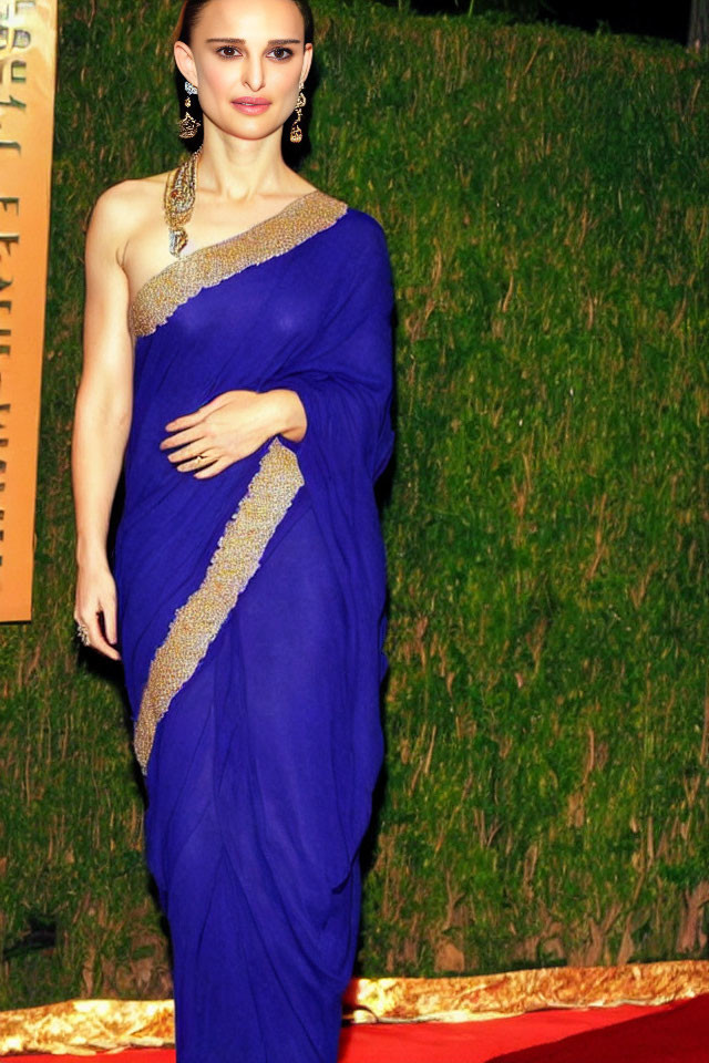 Elegant woman in blue sari with gold details on grassy backdrop