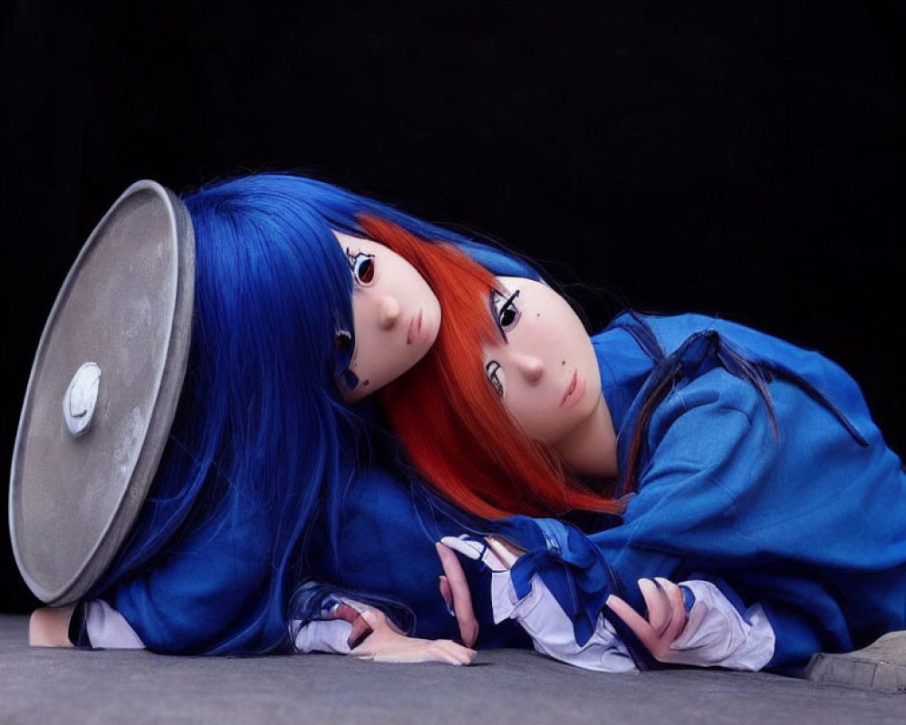 Vibrant blue and red hair individuals in blue outfits lying on the ground with overturned silver prop